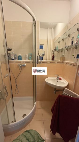 Badezimmer mit Dusche, Waschbecken und Regalen in einer 2-Zimmer-Wohnung.