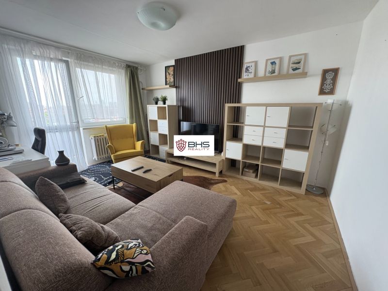 Wohnzimmer in einer 2-Zimmer-Wohnung mit einem bequemen Sofa und einem Boden in Holzoptik.
