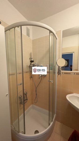 Badezimmer mit Duschkabine in einer 2-Zimmer-Wohnung, Fliesen in Cremefarbe.