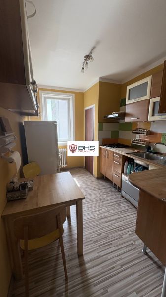 Küche mit gelben Wänden, Holzmöbeln und einem Boden mit Holzdekor in einer 2-Zimmer-Wohnung.
