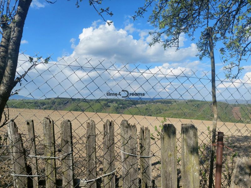 Blick auf Felder und Hügel in Budiná, umgeben von einem Zaun; Grundstücke - Wohnen.