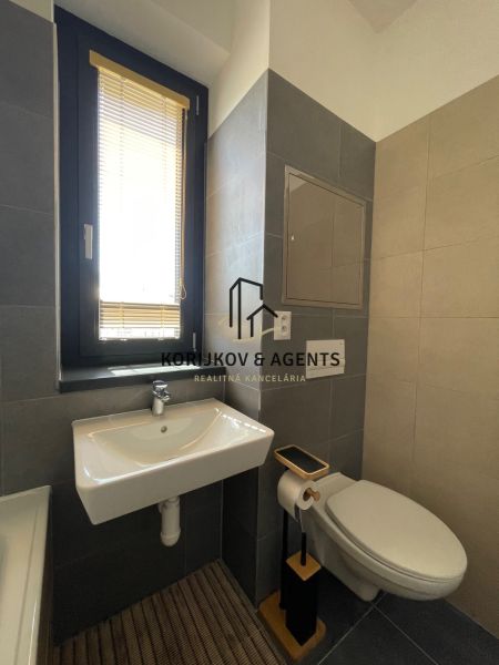 Badezimmer mit Waschbecken, WC und Fenster in einer 2-Zimmer-Wohnung.