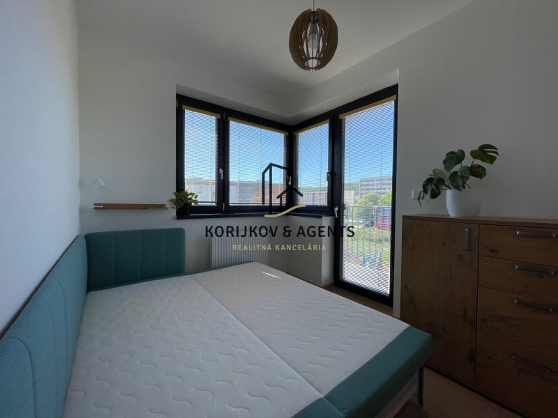 Schlafzimmer in einer 2-Zimmer-Wohnung mit Bett und Holzkommode, der Raum ist hell.