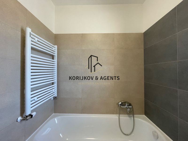 Badezimmer in einer 2-Zimmer-Wohnung mit Badewanne und kombinierten beige-grauen Fliesen.