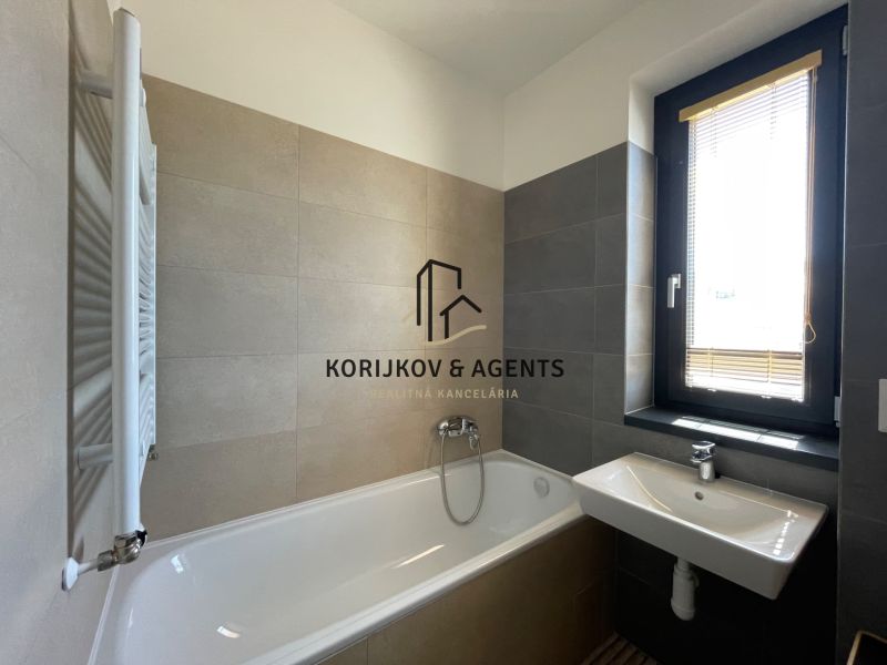 Badezimmer in einer 2-Zimmer-Wohnung mit Badewanne, Waschbecken und Fenster.