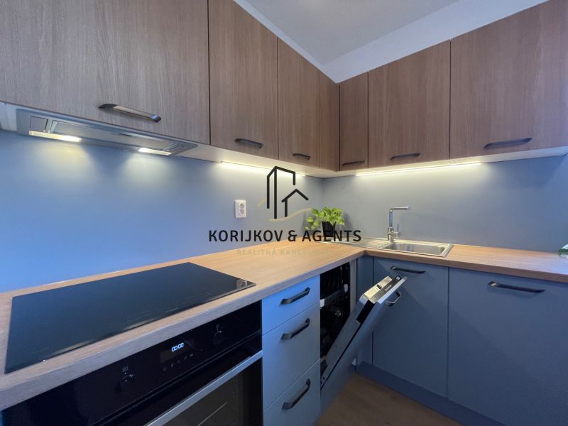 Moderne Küche in einer 2-Zimmer-Wohnung mit Holzboden und blauen Schränken.