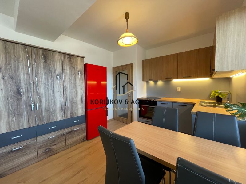 Küche in einer 2-Zimmer-Wohnung mit Schränken in Holzoptik und einem roten Kühlschrank.