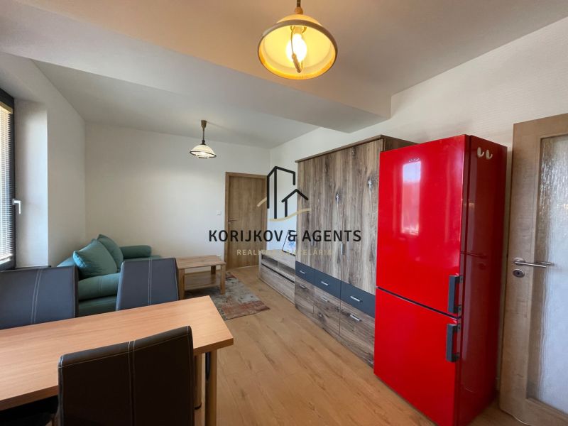 Wohnzimmer in einer 2-Zimmer-Wohnung mit Holzboden und rotem Kühlschrank.