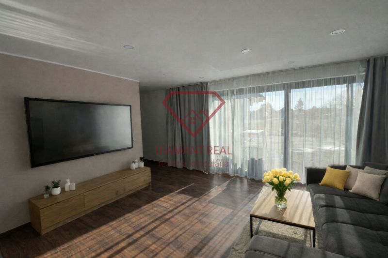 Wohnzimmer in einem Einfamilienhaus mit großem Fernseher, Sofa und Holzboden.