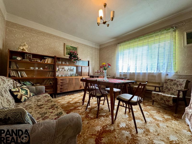 Wohnzimmer im Einfamilienhaus mit antiken Möbeln, Blumendekor und Teppich.