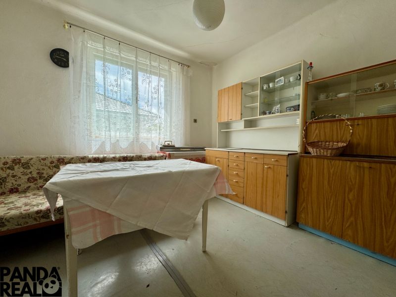 Ein Zimmer in einem Einfamilienhaus mit einem geblümten Sofa, einem Tisch und Holzmöbeln.