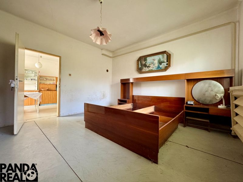 Ein Zimmer in einem Einfamilienhaus mit Retro-Möbeln und einer offenen Tür zur Küche.