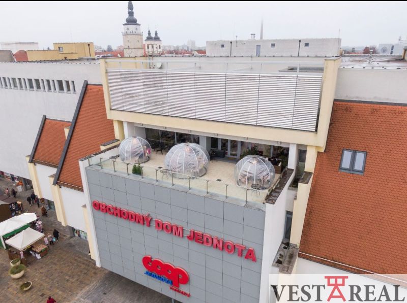 Kaufhaus Jednota am Dreifaltigkeitsplatz in Trnava mit Gastronomiebereichen auf der Terrasse.