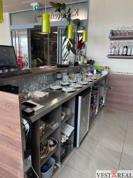 Eine Bartheke mit Getränken und Geschirr in einem Gastronomiebereich mit einem Boden in Holzoptik.