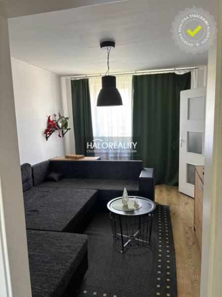 Wohnzimmer in einem Einfamilienhaus mit schwarzem Sofa und Boden in Holzoptik.