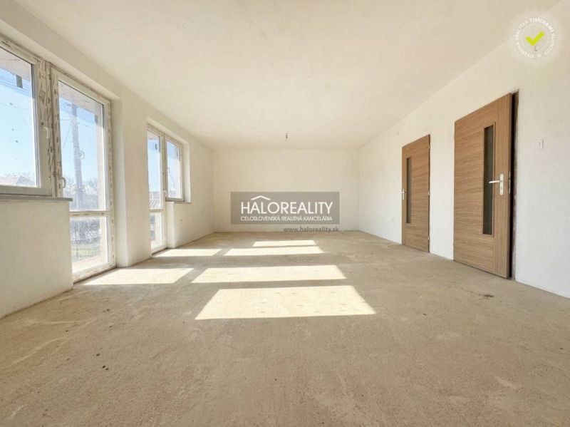 Geräumiges, helles Zimmer in einem Einfamilienhaus, große Fenster, Türen mit Holzdekor.