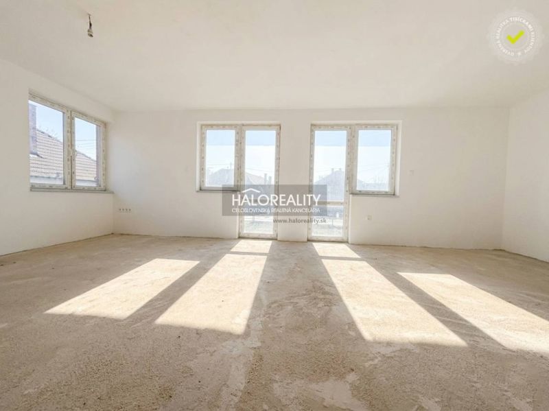 Ein Interieur in einem Einfamilienhaus mit großen Fenstern und einem unfertigen Boden.
