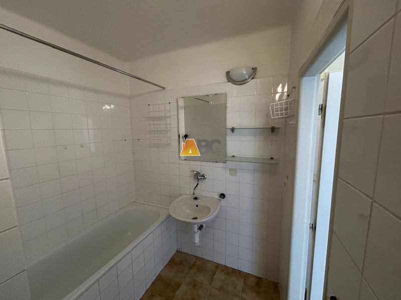 Badezimmer mit Badewanne in einer 2-Zimmer-Wohnung mit Fliesen.