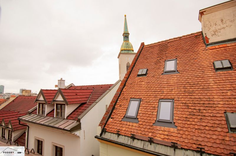 Der Kirchturm, der über die Dächer in der Beblavého Straße in Bratislava hinausragt.
