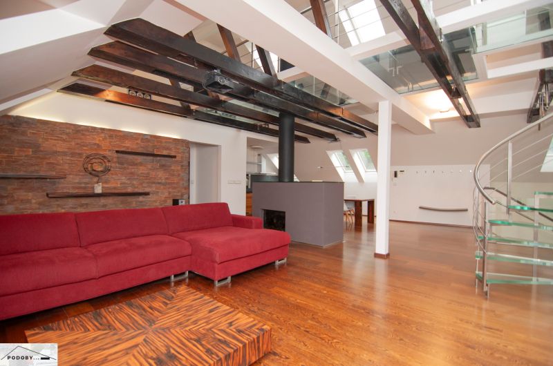 Dachboden-Wohnbereich mit großem rotem Sofa und Holzboden in einer 3-Zimmer-Wohnung.