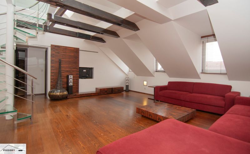 Ein Loft-Wohnbereich in einer 3-Zimmer-Wohnung mit einem roten Sofa und einem Boden in Holzoptik.
