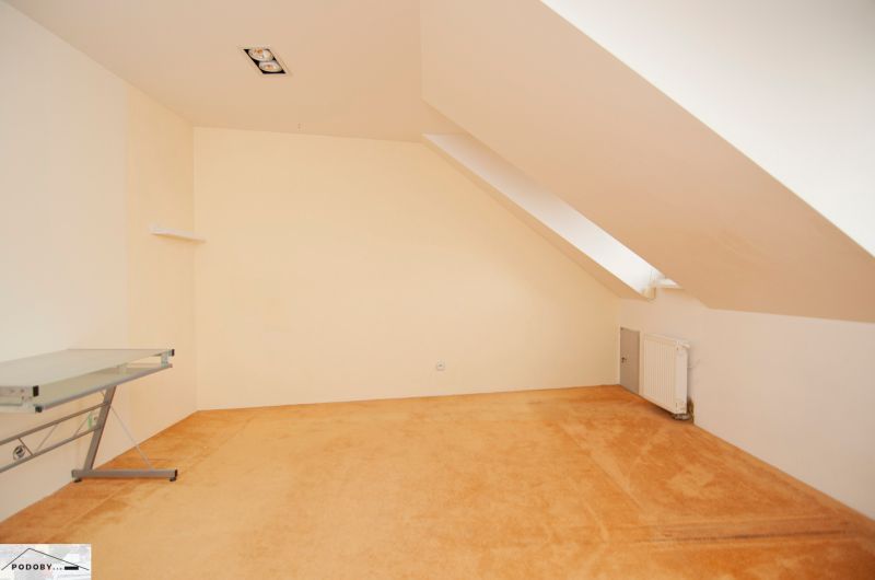 Dachzimmer mit Schreibtisch und Heizkörper in einer 3-Zimmer-Wohnung.