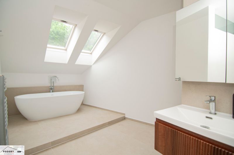 Ein Badezimmer mit Dachfenstern, freistehender Badewanne und Waschbecken in einer 3-Zimmer-Wohnung.