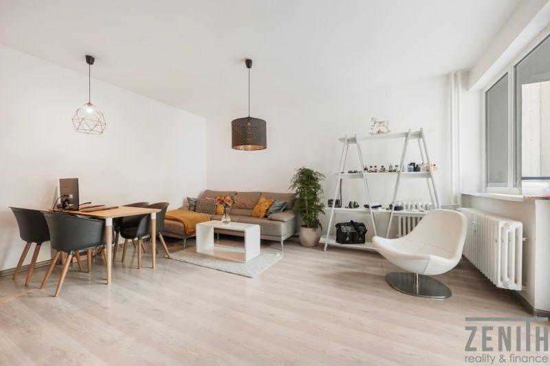 Wohnzimmer in einer Zweizimmerwohnung mit hellem Boden in Holzoptik, modernen Möbeln und Dekorationen.