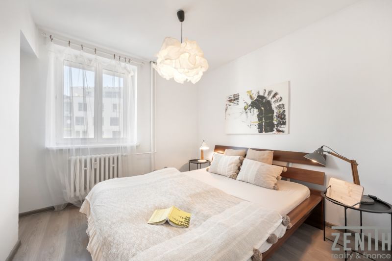 Helles Schlafzimmer mit einem Holzbett, einem Bild an der Wand und einem Boden mit Holzdekor.