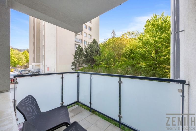Balkon einer 2-Zimmer-Wohnung in Bratislava - Altstadt mit Blick auf Grünflächen und ein Gebäude.
