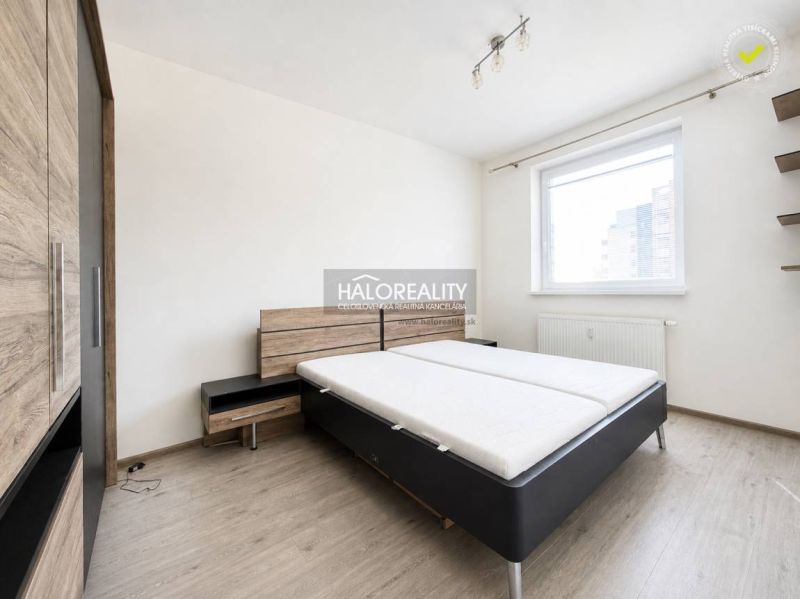 Schlafzimmer mit Bett, Kleiderschrank und Holzboden in einer Zweizimmerwohnung.