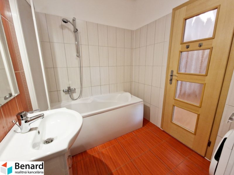 Badezimmer mit hellen Fliesen und rotem Bodenbelag in einer 3-Zimmer-Wohnung.