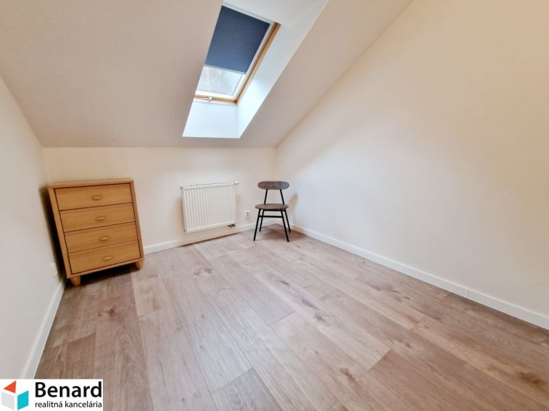 Ein Zimmer in einer 3-Zimmer-Wohnung mit einem Boden in Holzoptik, einer Kommode und einem Stuhl.
