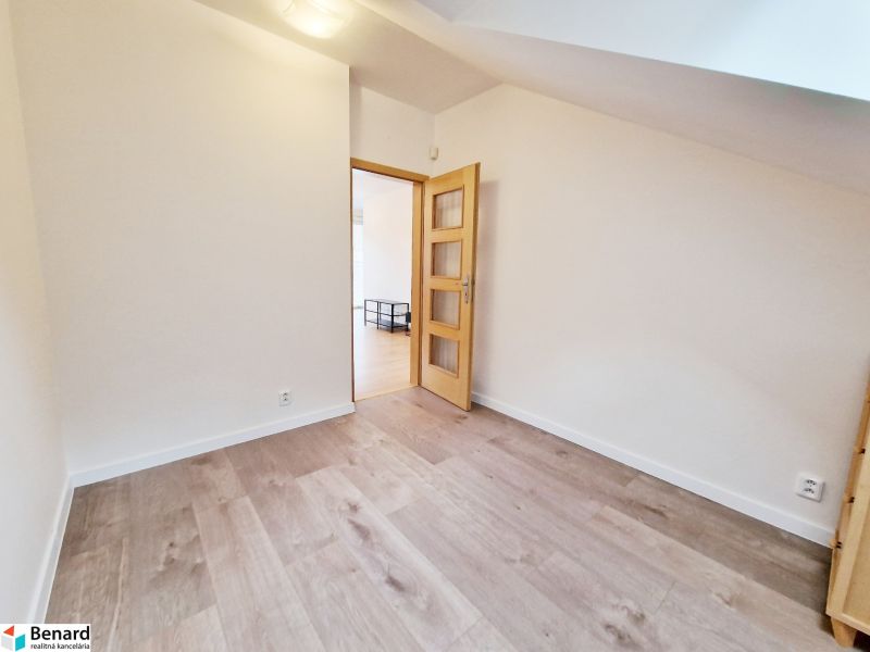 Ein Zimmer in einer 3-Zimmer-Wohnung mit einem Boden in Holzoptik und hellen Wänden.