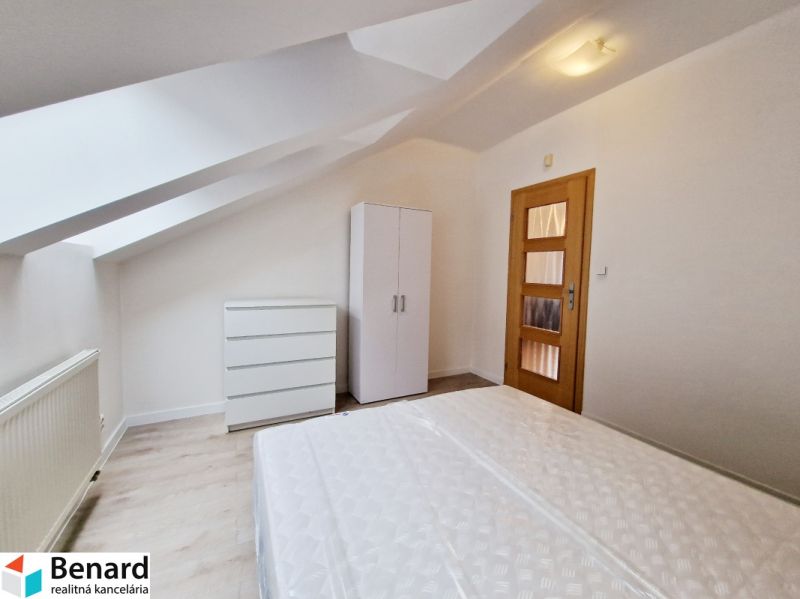 Dachbodenschlafzimmer in einer 3-Zimmer-Wohnung mit weißen Möbeln und einem Boden in Holzoptik.