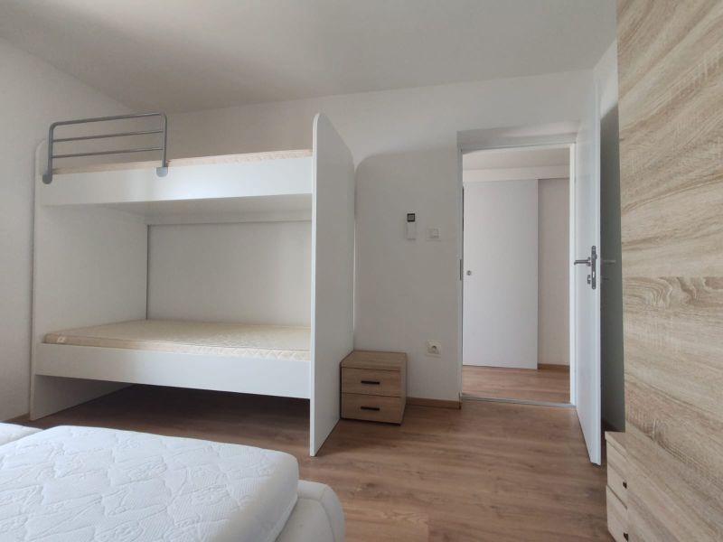 Ein Schlafzimmer mit einem Etagenbett, einem Boden mit Holzdekor und Stauraum in einem Einfamilienhaus.