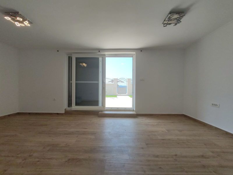 Ein Zimmer mit einem Holzboden und Balkontüren in einem Einfamilienhaus.