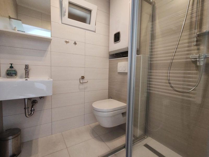 Badezimmer im Einfamilienhaus mit Waschbecken, Duschkabine und Hänge-WC.