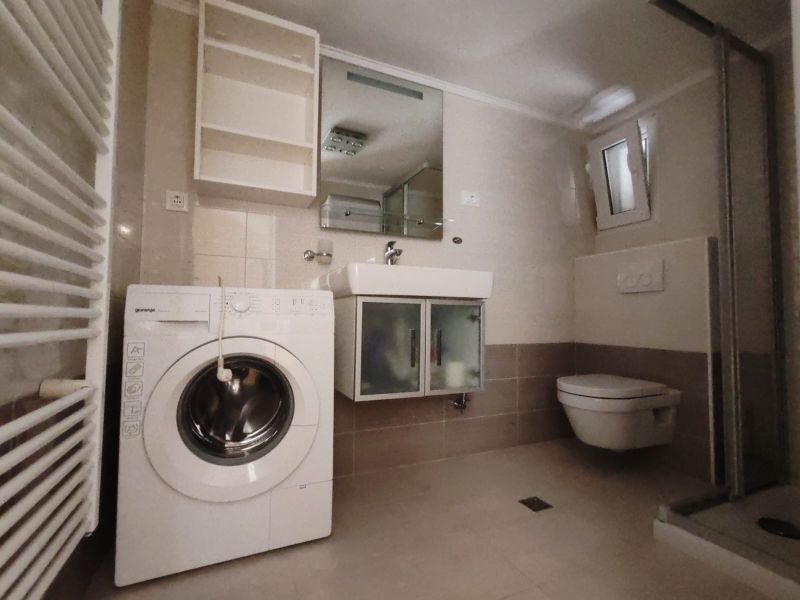 Badezimmer in einem Einfamilienhaus mit Waschmaschine, Waschbecken, Duschkabine und Toilette.