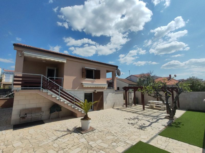 Ein Einfamilienhaus in Bibinje mit Treppen, Terrasse und Laubengang, umgeben von einem Garten.