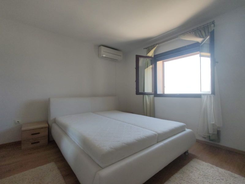 Schlafzimmer in einem Einfamilienhaus mit großem Fenster und Bett, Boden mit Holzdekor.