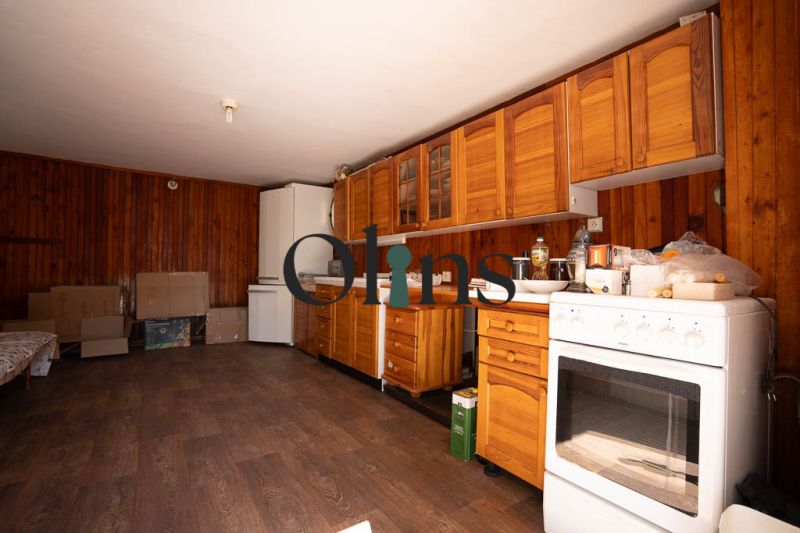 Küche in einem Einfamilienhaus mit Holzschränken und einem Boden in Holzoptik.