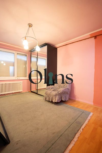 Ein Zimmer in einem Einfamilienhaus mit einem Boden in Holzoptik, einem Spiegelschrank und einem Sessel.