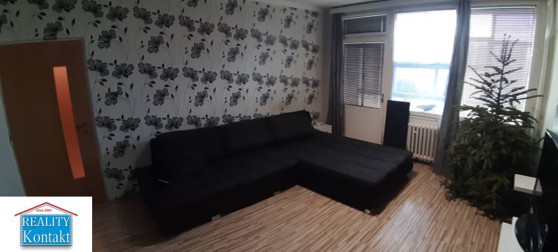 Wohnzimmer in einer 2-Zimmer-Wohnung mit einer Blumentapete und einem Holzboden.