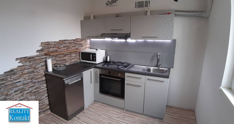 Küche in einer 2-Zimmer-Wohnung mit Holzboden und Steinwand.