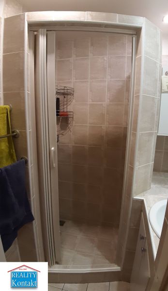 Duschkabine im Badezimmer mit Fliesen in einer 2-Zimmer-Wohnung.