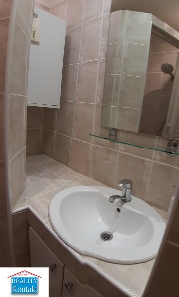 Kleines Badezimmer mit Waschbecken und Spiegel in einer Zweizimmerwohnung.
