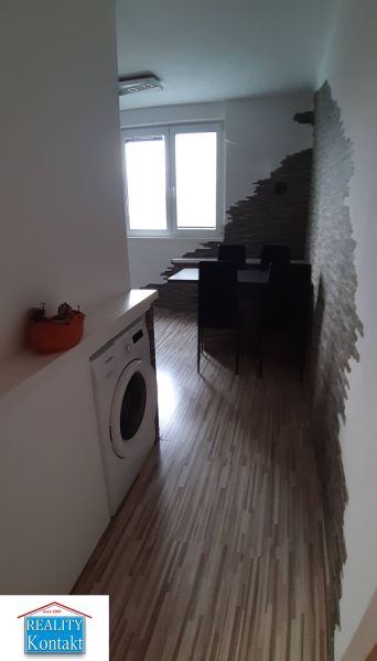 Essbereich mit Holzboden, Waschmaschine und interessanter Wand in einer 2-Zimmer-Wohnung.