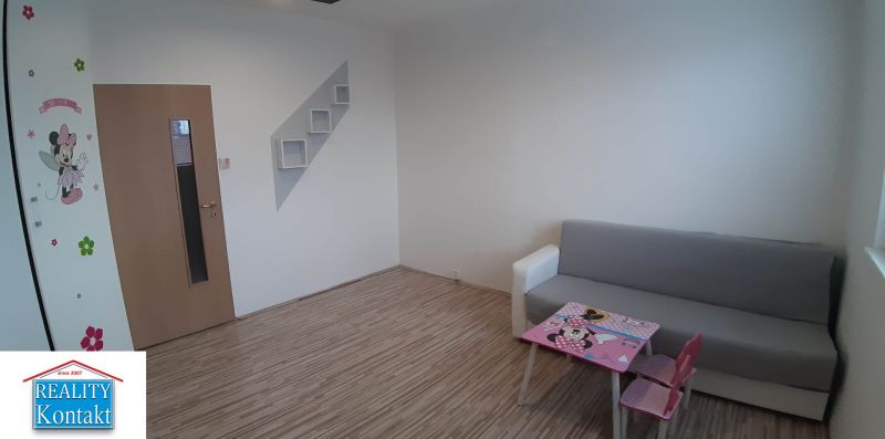 Wohnzimmer in einer 2-Zimmer-Wohnung mit Holzboden und Kindermöbeln.