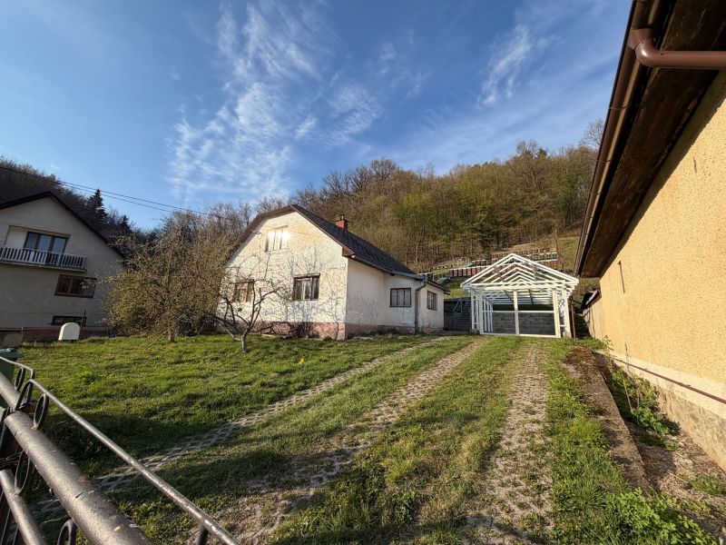 Ein Einfamilienhaus in Štós, umgeben von Grün und einer Holzkonstruktion eines Unterstands.